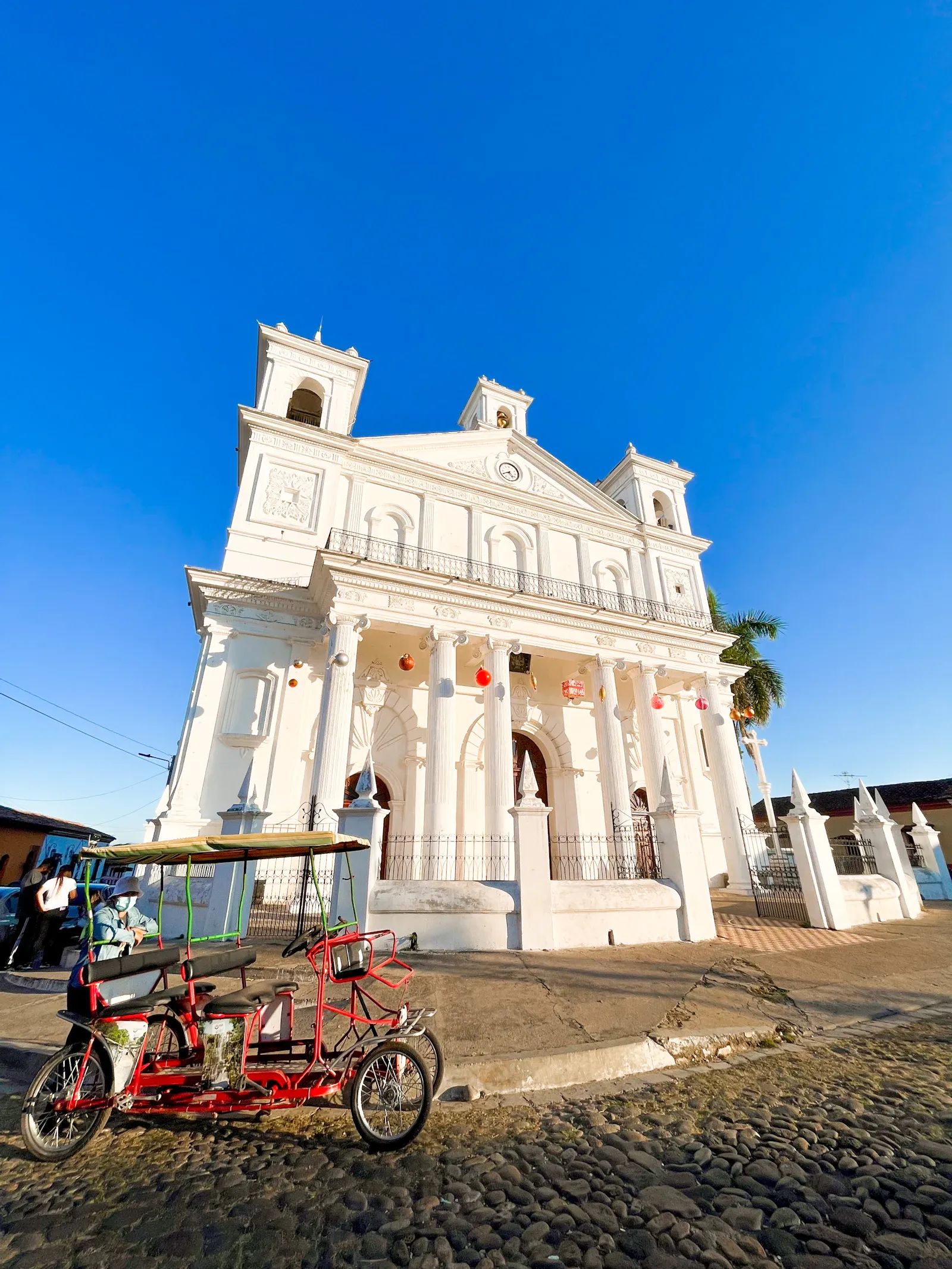 A motorcycle parked in front of a white colonial building in Suchitoto